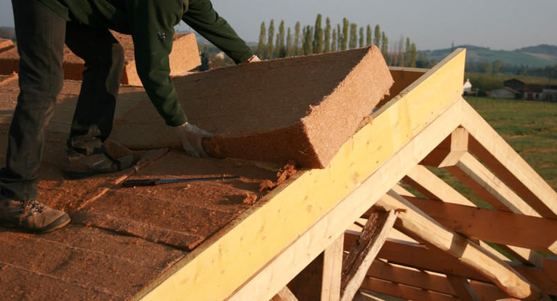 ouvrier isolant une toiture avec de la laine de bois